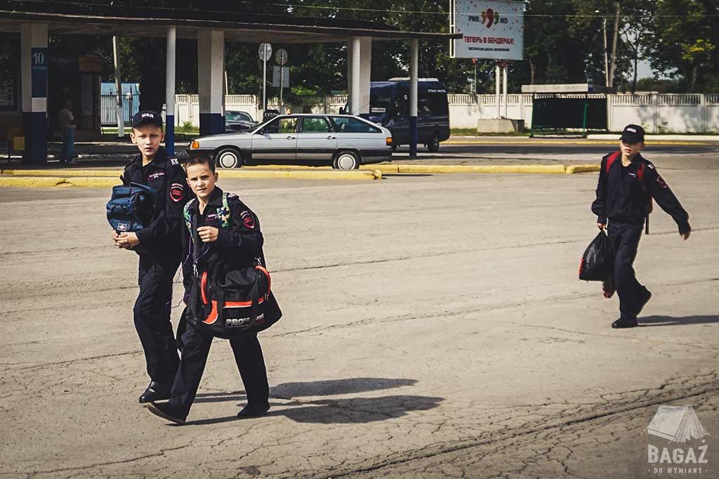 chłopcy w wieku szkolnym w mundurach wracają ze szkoły