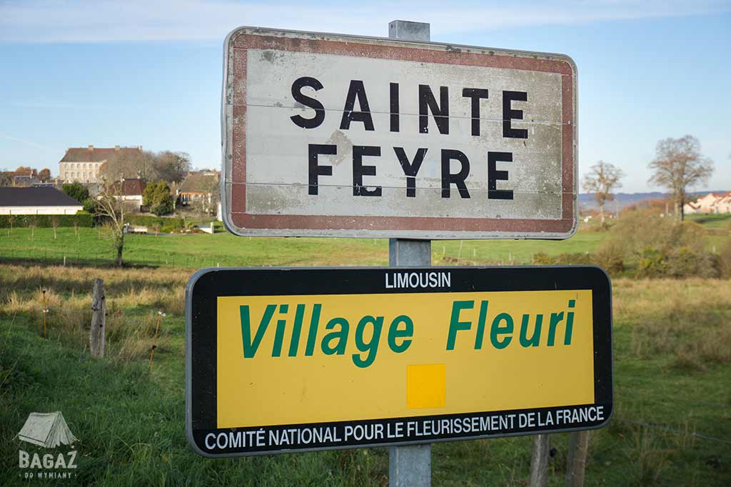 tablica wjazdowa do francuskiej wioski Sainte Feyre z widokiem na zamek w tle