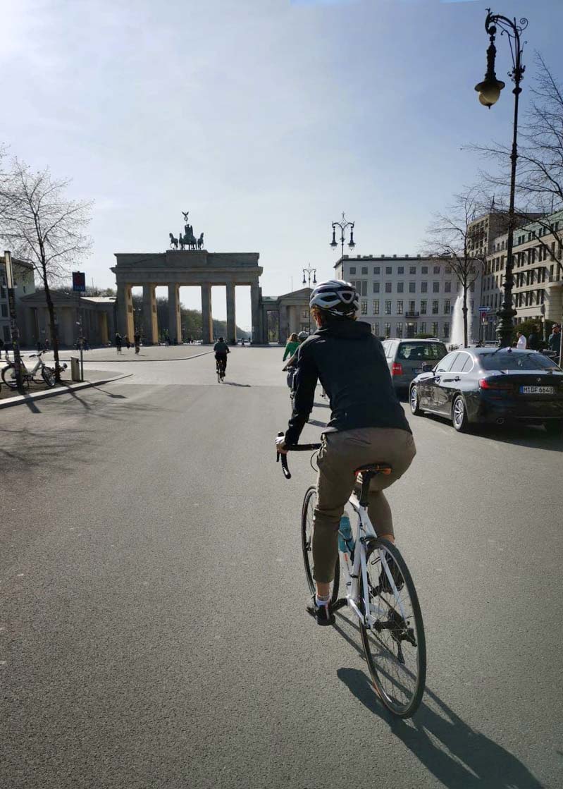 rowerzysta na tle bramy bramy brandenburskiej w Berlinie podczas epidemii koronawirusa