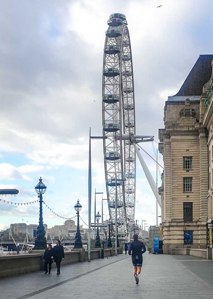 mężczyzna uprawiający jogging biegnący w stronę london eye